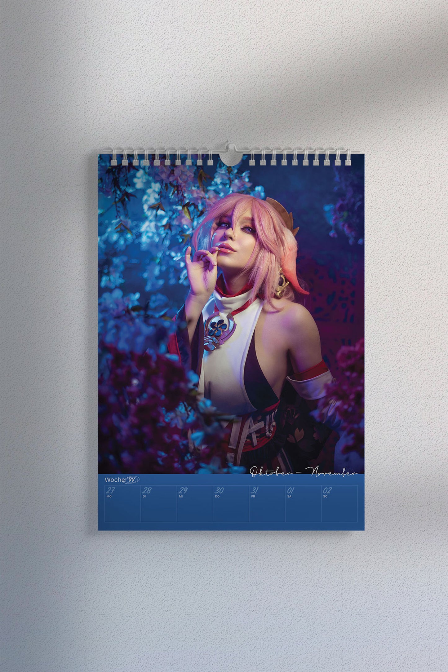 Kalenderseite mit Cosplay-Foto einer Figur mit rosa Haaren und Ohrenaufsätzen in einem violett-blau blühenden Blumenmeer. Unten der Wochenplaner „Oktober–November, Woche 44“.