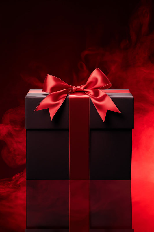 Schwarze Geschenkbox mit glänzend roter Schleife und breitem roten Band, stehend vor rotem Rauchhintergrund auf reflektierender Oberfläche.