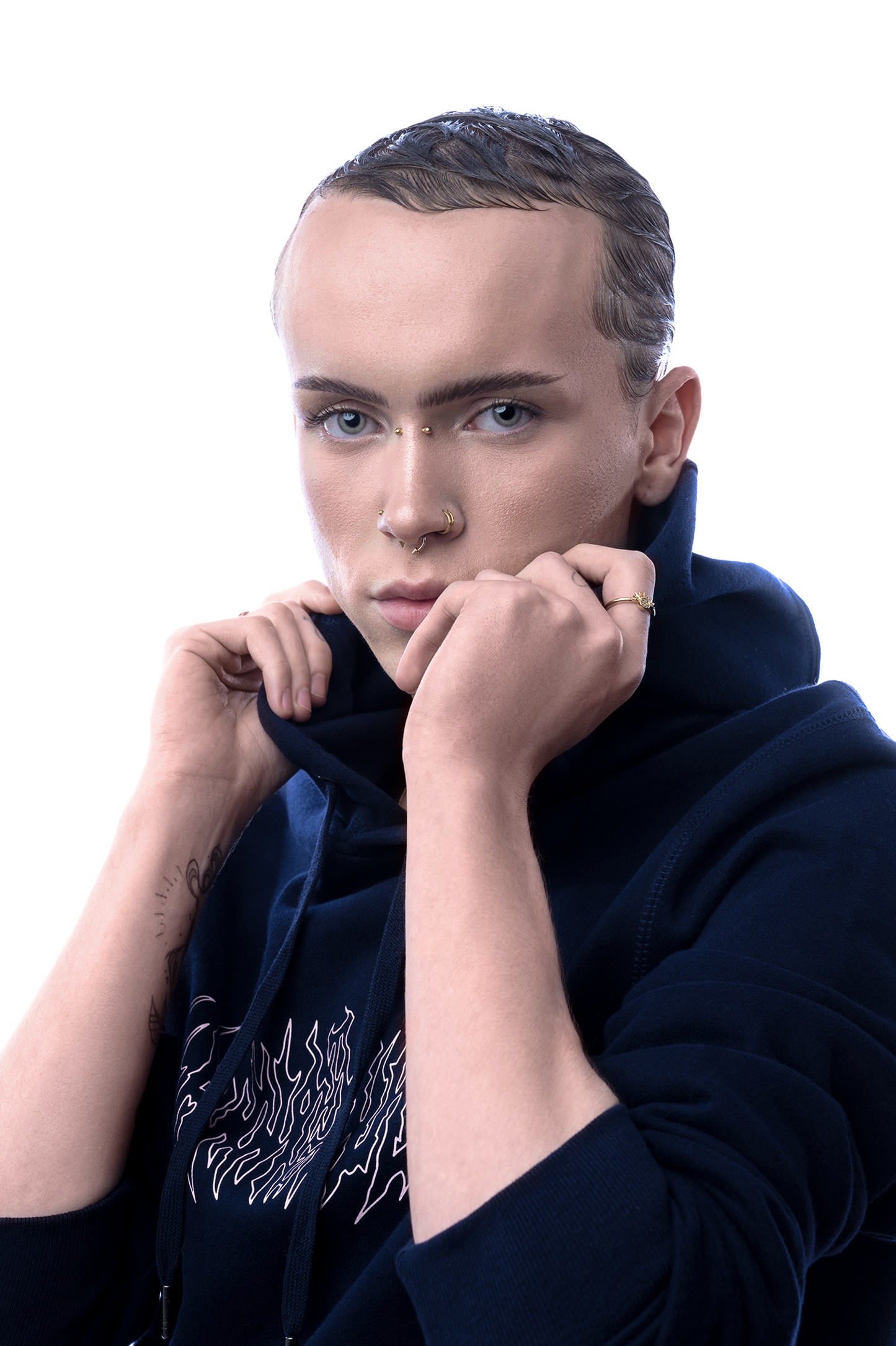 Gleiche Person zieht den Hoodiekragen leicht hoch, Fokus auf Gesicht und obere Partie des Schriftzugs.