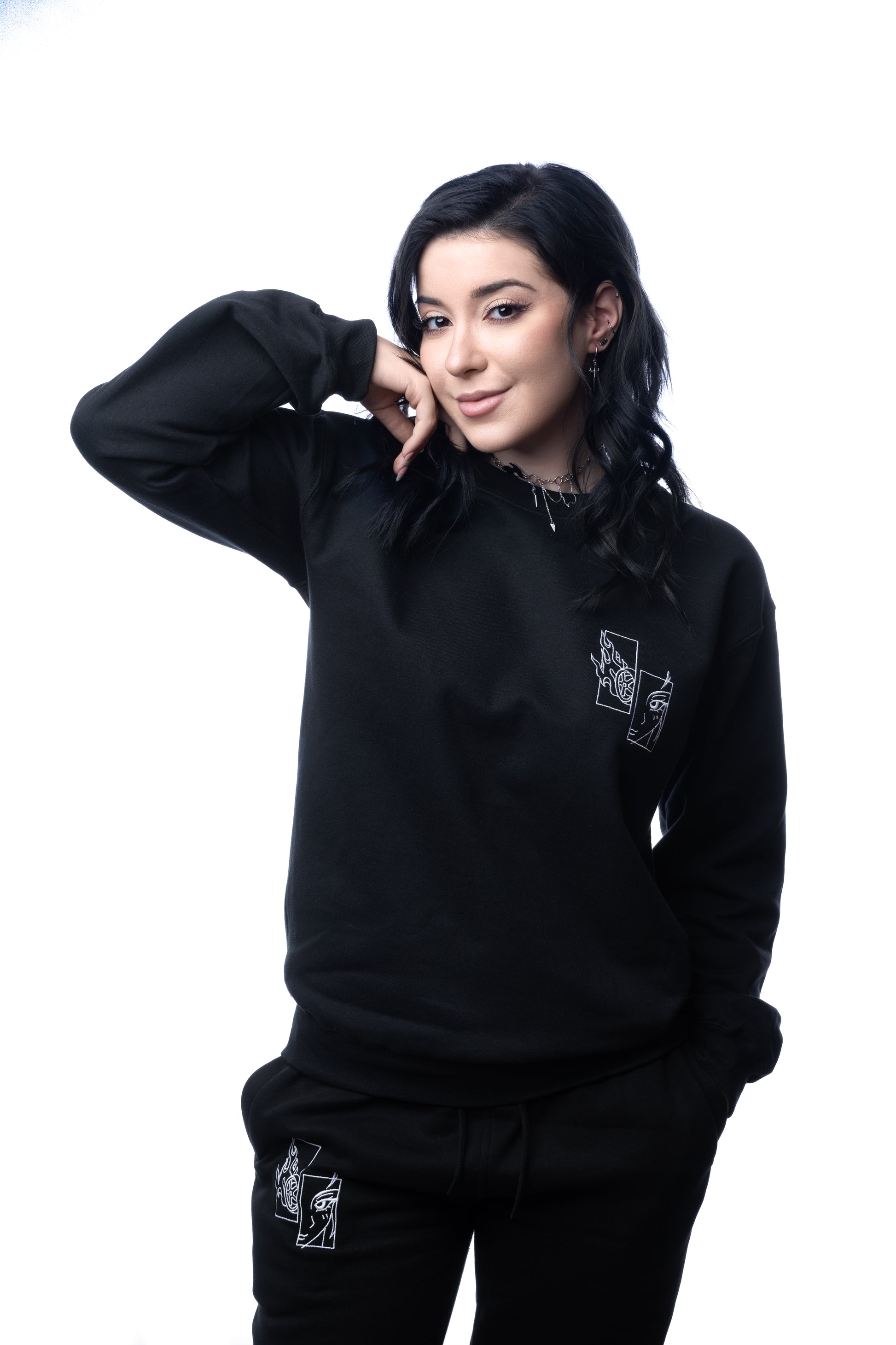 Schwarzer Sweatshirt mit weißem Sticklogo links auf der Brust, präsentiert in entspannter Pose mit Händen in den Taschen.