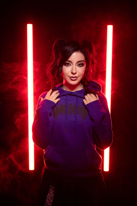 Violetter Hoodie mit schwarzem Frontprint, getragen vor leuchtenden Lichtstäben in Nebelkulisse.