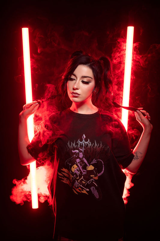 Schwarzes T-Shirt mit Teufelin-Motiv im roten Studiolicht, die zentrale Figur ist umgeben von Schattenflammen und dynamischen Effekten.