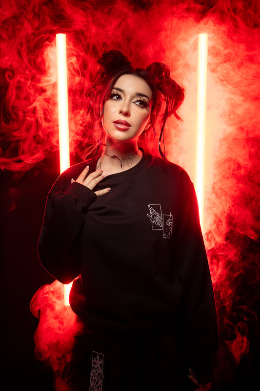 Schwarzes Sweatshirt mit kleinem Sticklogo auf der Brust, fotografiert im roten Neonlicht mit Nebeleffekt.