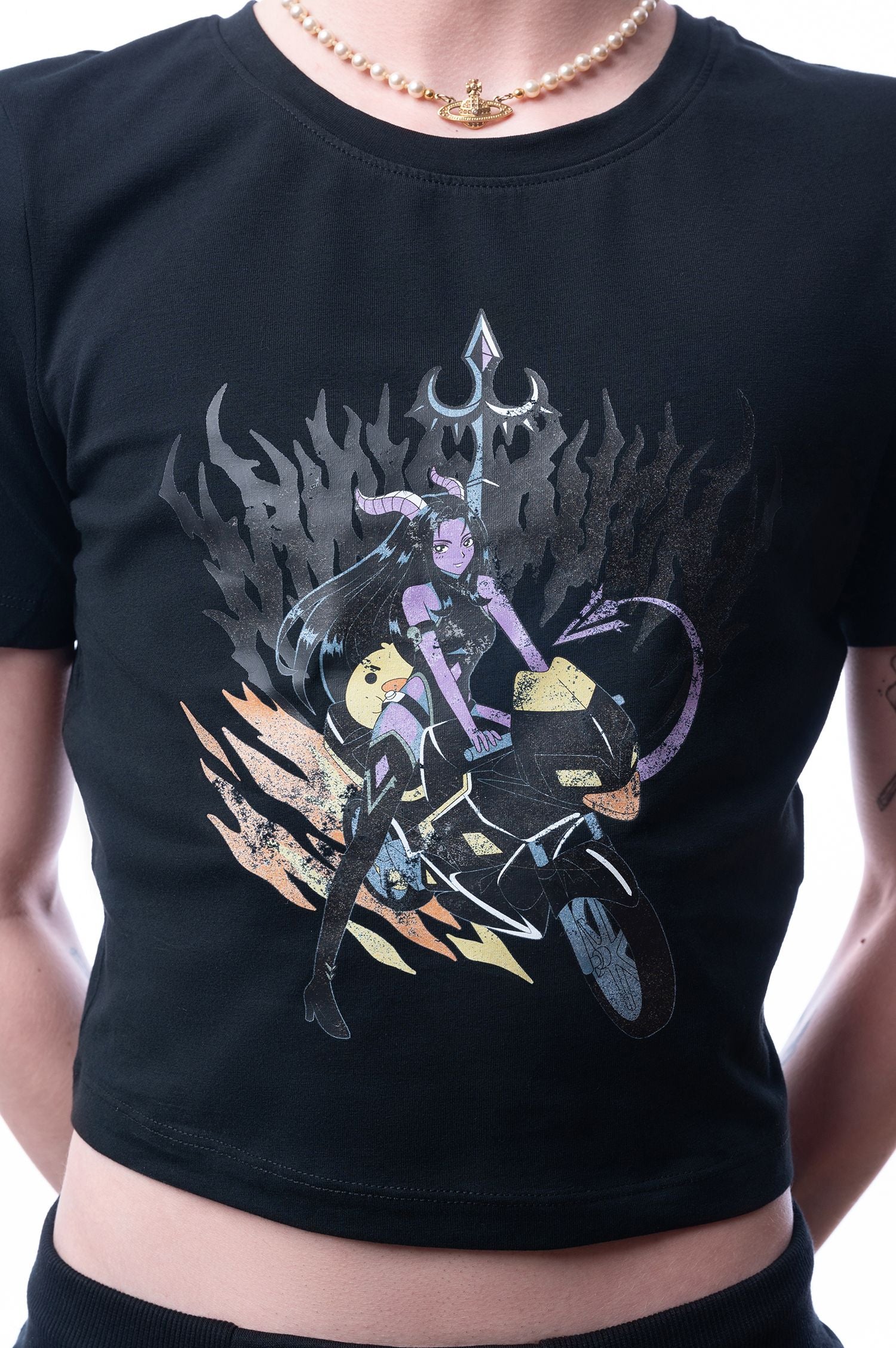 Schwarzes T-Shirt mit farbigem Frontprint: Eine lila Dämonin mit Hörnern sitzt auf einem Motorrad vor schwarzen Flammen; Nahaufnahme des Designs auf Brusthöhe.
