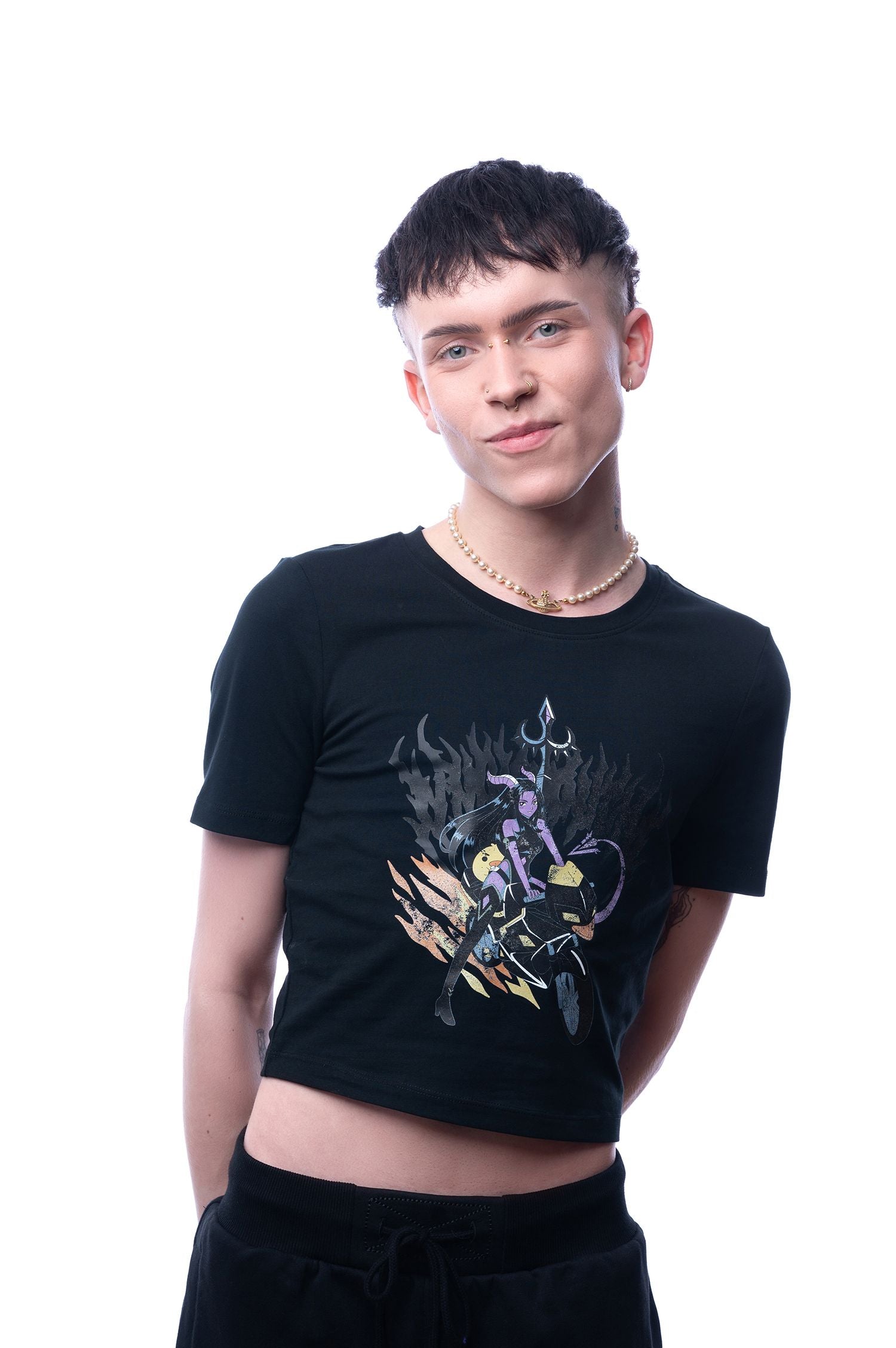 Schwarzes Cropped-T-Shirt mit Anime-Motiv, getragen von einem männlich gelesenen Model; Frontalansicht mit leichtem Lächeln, Fokus auf das Shirt.